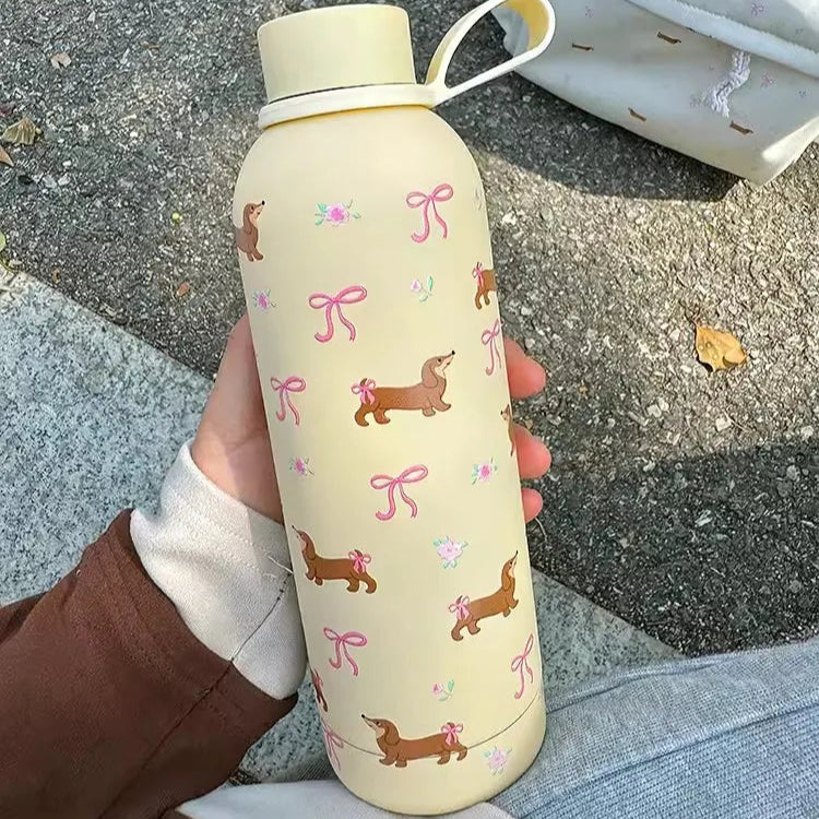 Two stainless steel water bottles with a cream color and adorned with pink and brown dachshund designs.