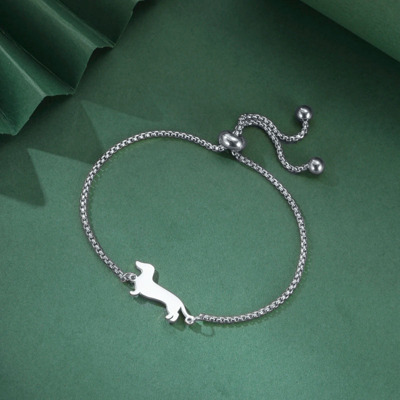 Silver bracelet with a dachshund charm on a green background