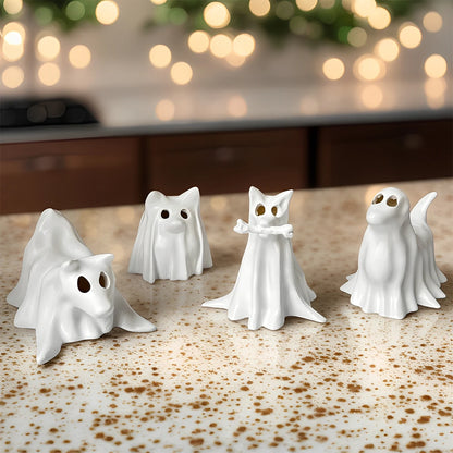 Four white ghost-shaped figurines with gold eyes are arranged on a speckled beige countertop with a blurred kitchen background and warm string lights.