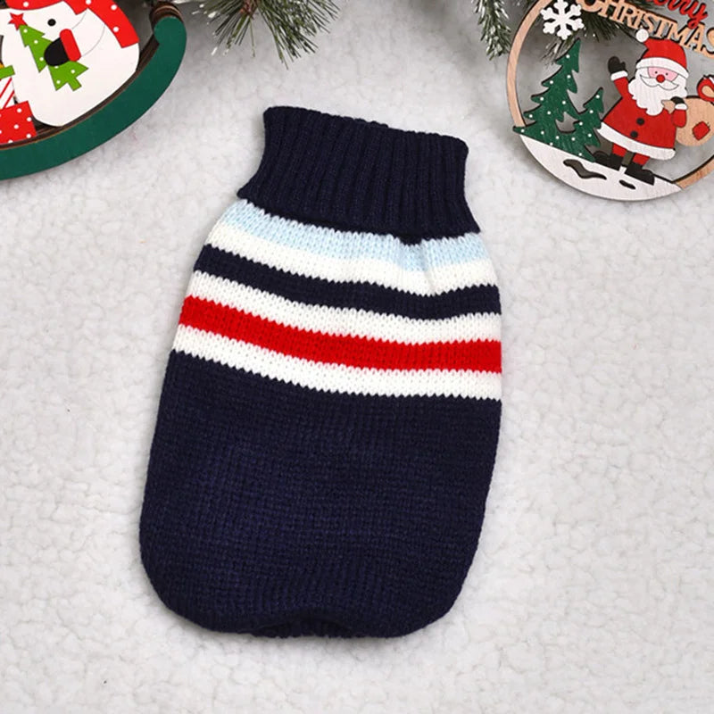 Navy blue knitted sweater with red and white stripes on a textured surface with Christmas decorations.