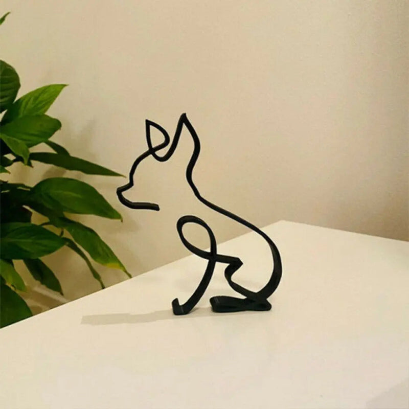 Black wire sculpture of a cat on a white surface with a plant in the background