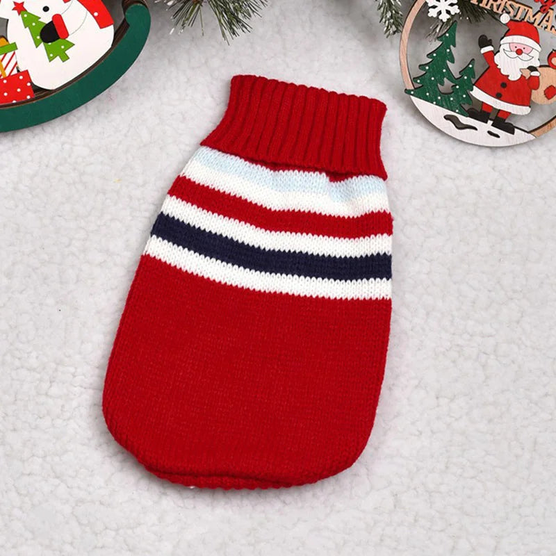 Red and white striped pet sweater on a textured surface with Christmas decorations.