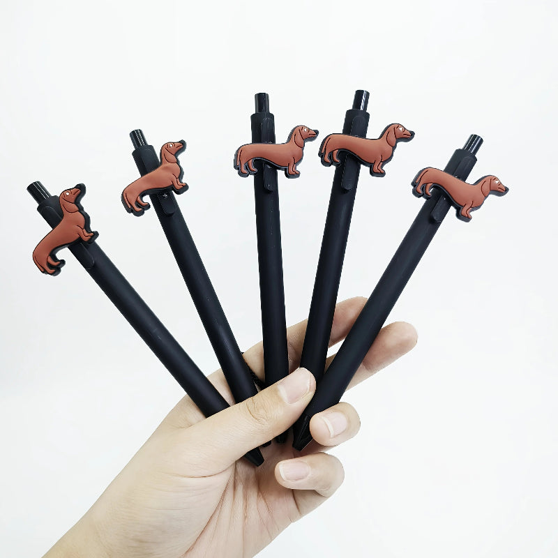 Five black pens with dachshund-shaped tips held in a hand against a white background