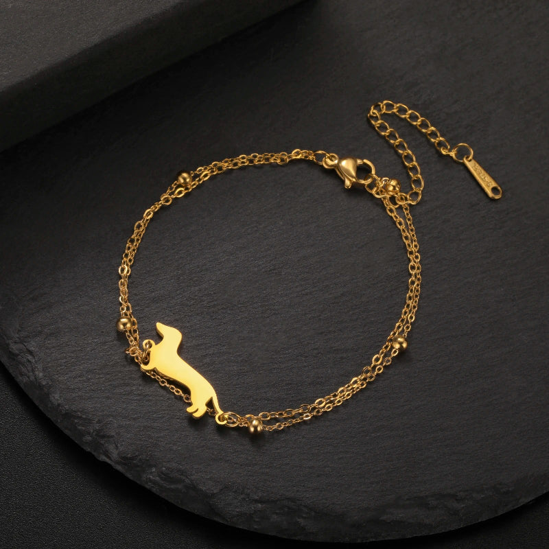 Gold bracelet with a dog silhouette on a dark surface
