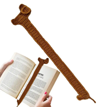 Brown crocheted bookmark with a decorative element over an open book.