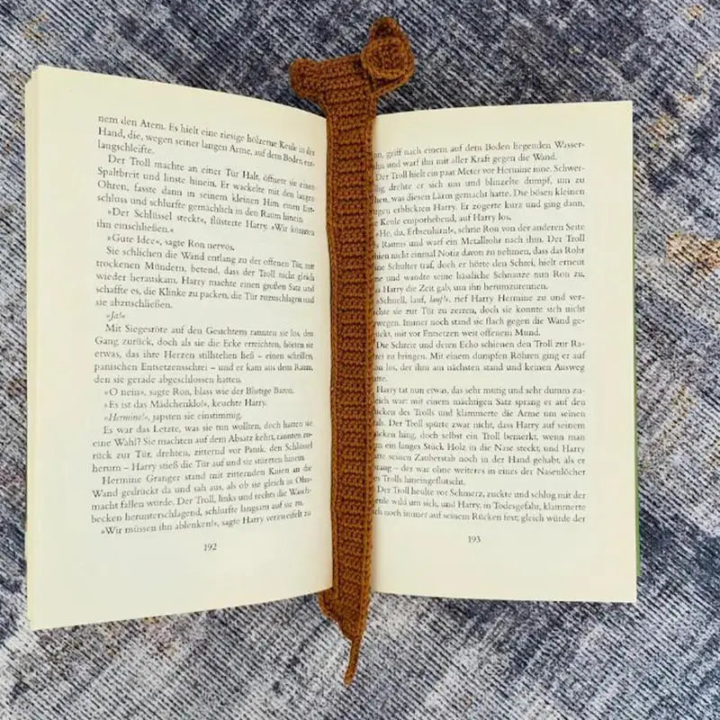 Open book with a brown crocheted bookmark on a textured surface