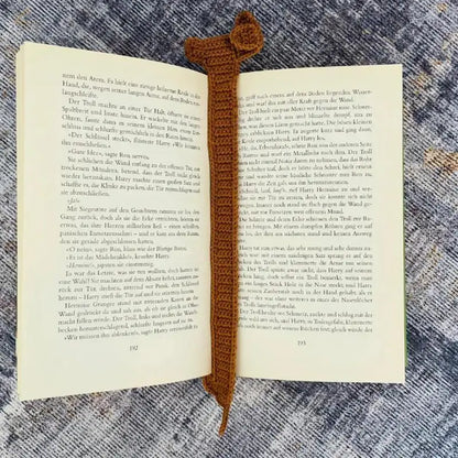 Open book with a brown crocheted bookmark on a textured surface